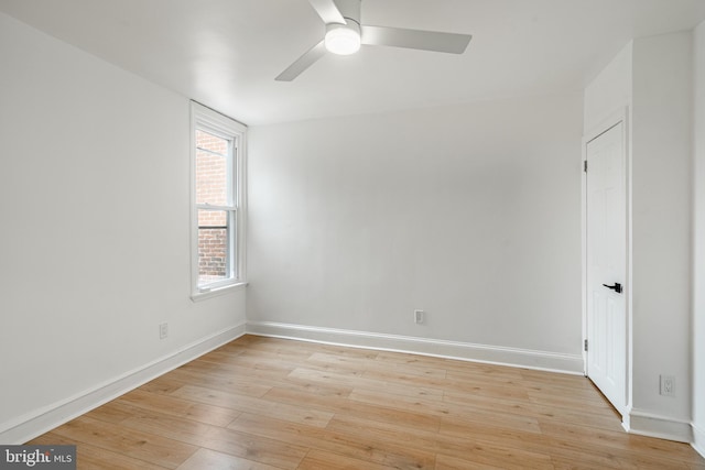 spare room with light wood finished floors, a ceiling fan, and baseboards