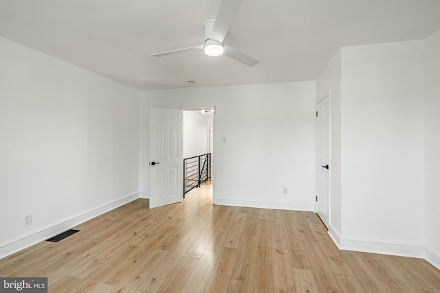 spare room featuring a ceiling fan, visible vents, light wood-style flooring, and baseboards