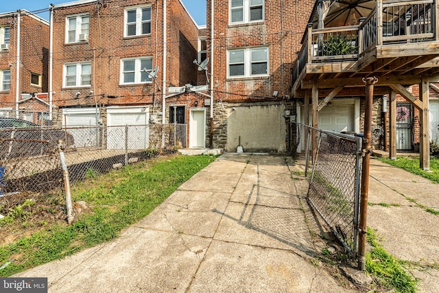 view of property featuring a garage, fence, concrete driveway, and brick siding