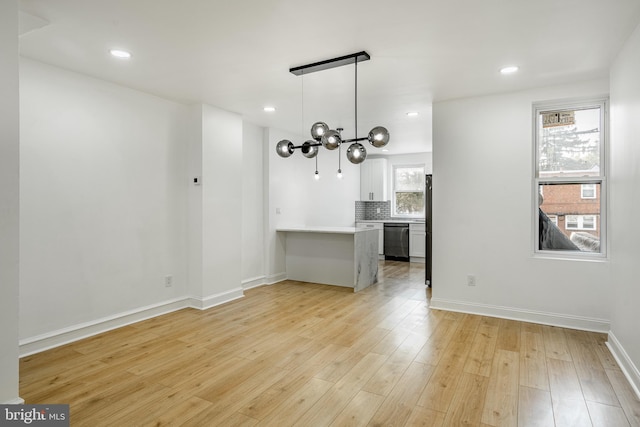 unfurnished living room featuring baseboards, light wood finished floors, recessed lighting, and an inviting chandelier