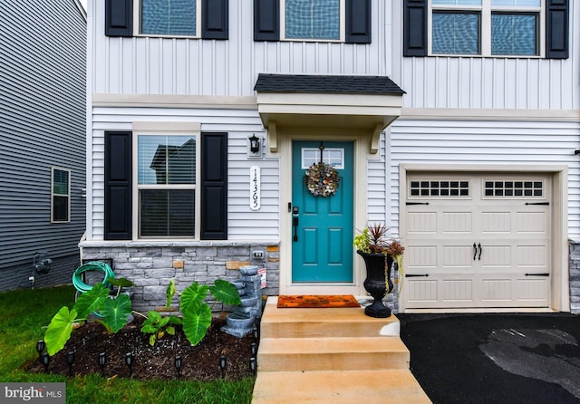 view of exterior entry with board and batten siding, stone siding, and a garage