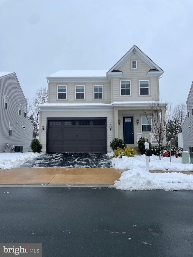 traditional-style house with an attached garage, aphalt driveway, and central AC