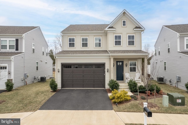 traditional-style home with central AC, a porch, an attached garage, a shingled roof, and driveway
