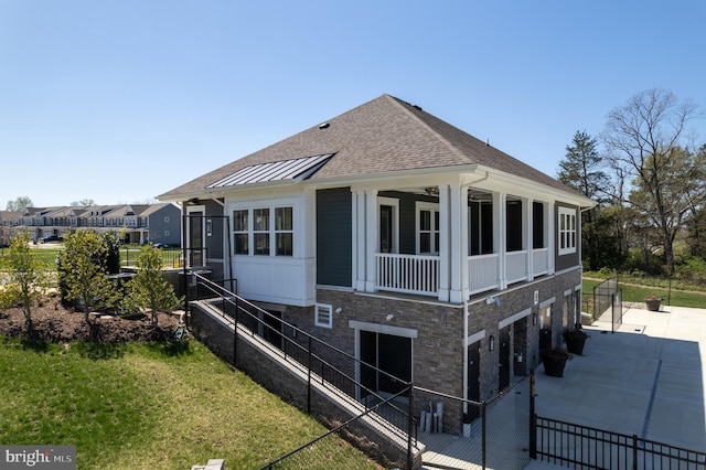 view of side of property featuring a lawn, roof with shingles, fence, stone siding, and concrete driveway