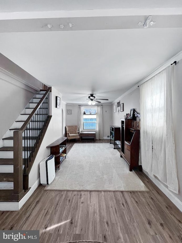 living area with a ceiling fan, stairs, baseboards, and wood finished floors