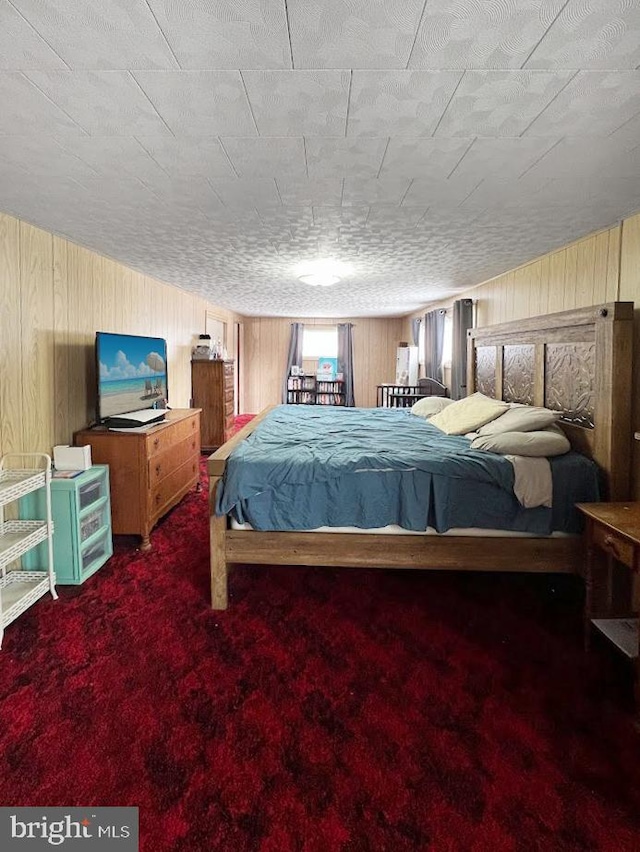 bedroom featuring wooden walls and dark carpet