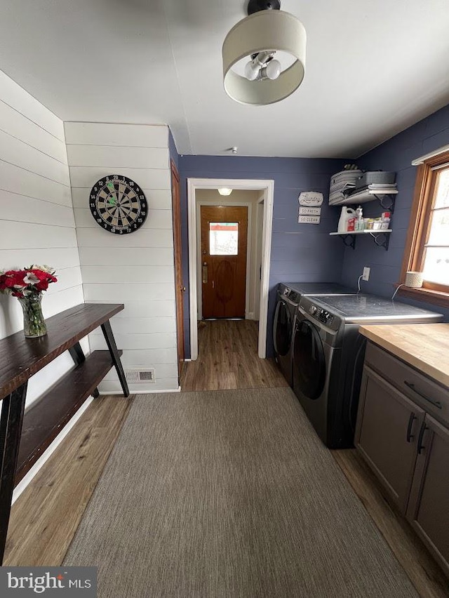 laundry area featuring dark wood-style floors, visible vents, washing machine and clothes dryer, and cabinet space