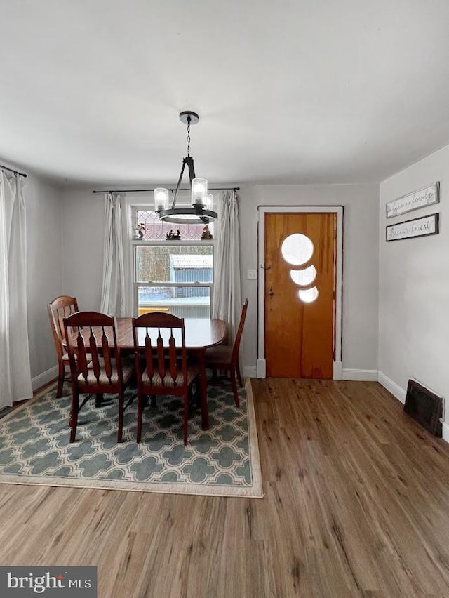 dining area featuring a chandelier, wood finished floors, and baseboards