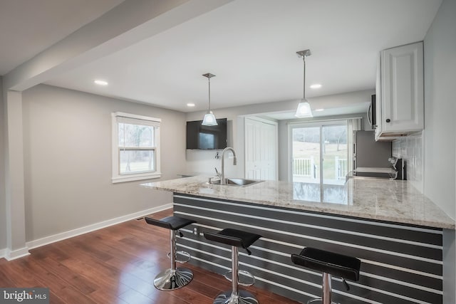 kitchen with white cabinetry, a sink, a peninsula, and light stone countertops