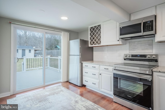 kitchen featuring tasteful backsplash, appliances with stainless steel finishes, light stone countertops, and white cabinets