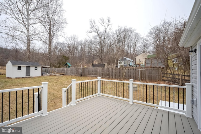 deck featuring an outbuilding, a fenced backyard, a lawn, and a shed