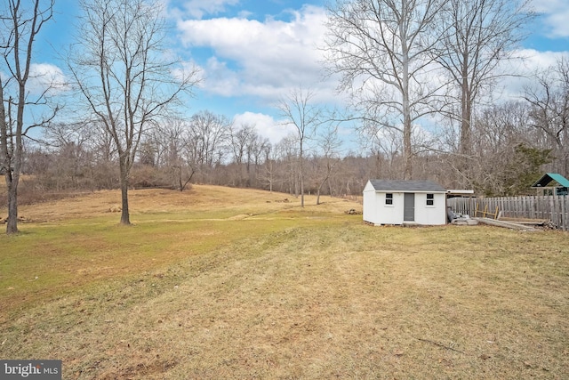 view of yard featuring an outbuilding, fence, and a shed