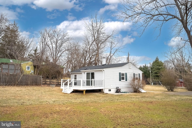 back of house featuring a chimney, fence, a deck, and a lawn