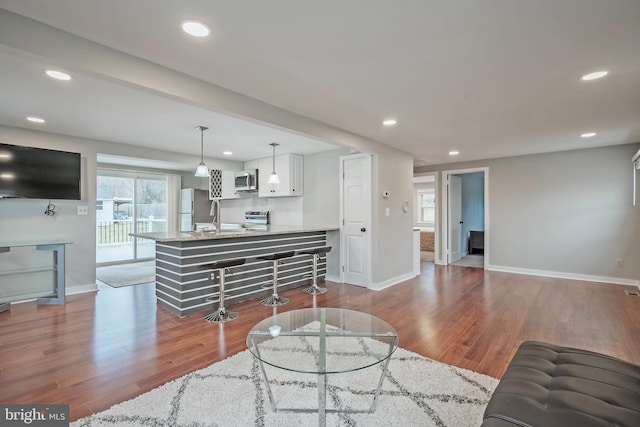 living room featuring recessed lighting, light wood-style flooring, and baseboards