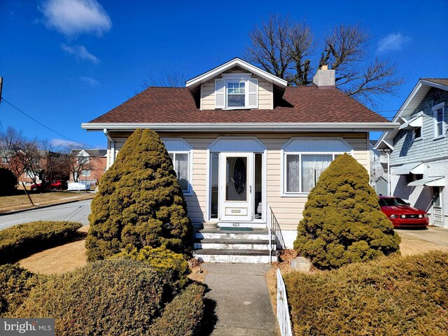 bungalow-style home with a shingled roof and a chimney