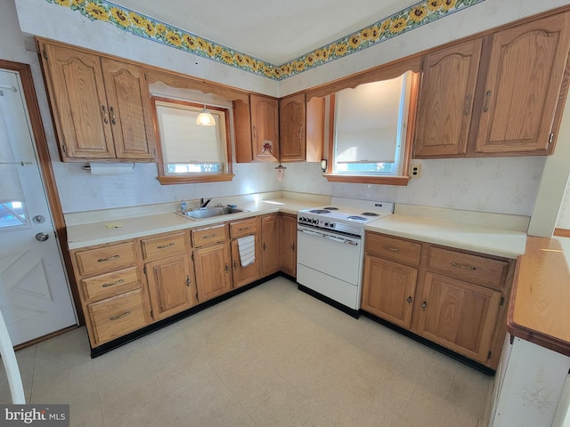 kitchen with light countertops, electric stove, brown cabinets, and a sink