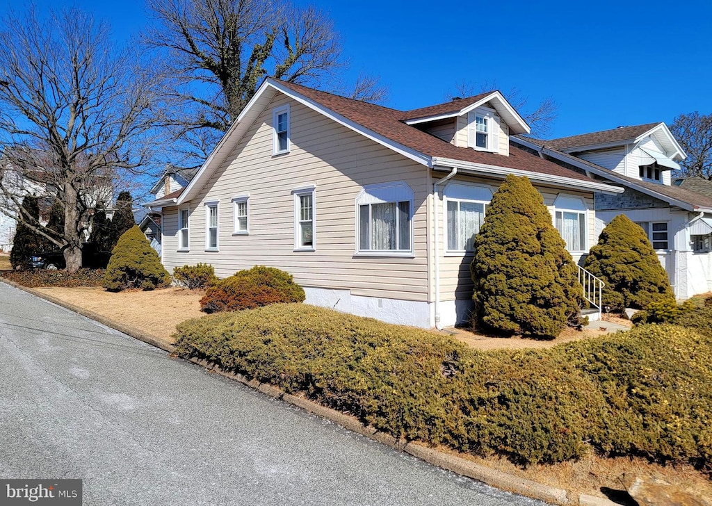 view of side of home with roof with shingles