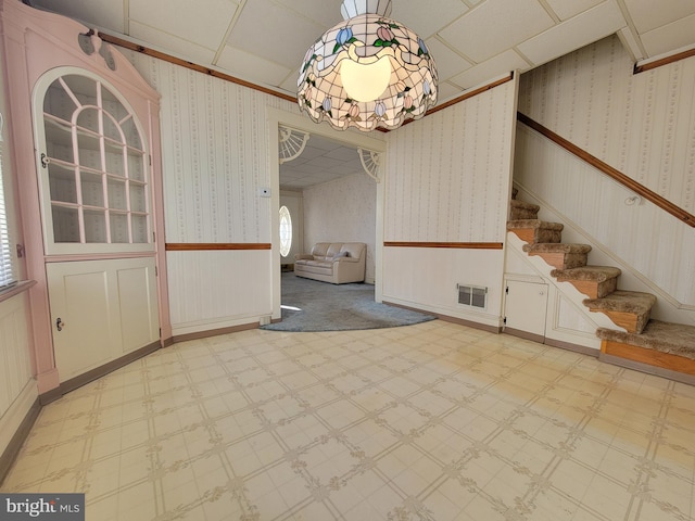 unfurnished dining area featuring wallpapered walls, visible vents, a wainscoted wall, and tile patterned floors