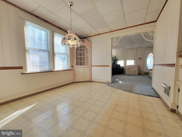 unfurnished dining area featuring crown molding, light floors, wainscoting, and wallpapered walls