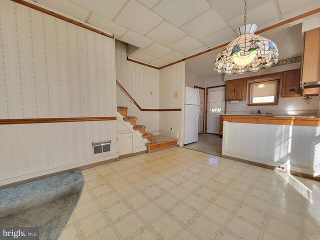 kitchen featuring wallpapered walls, wainscoting, light floors, and freestanding refrigerator