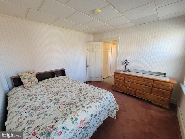 bedroom with a drop ceiling, dark carpet, and wallpapered walls