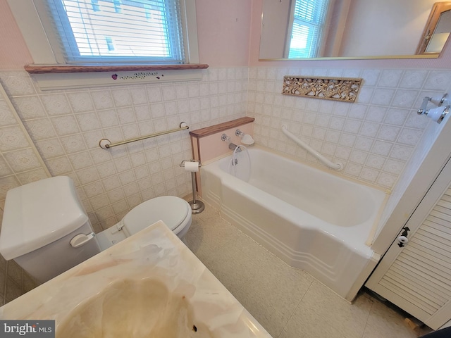 bathroom with toilet, a garden tub, tile patterned flooring, and tile walls