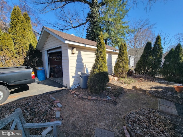 view of side of home with a detached garage and an outbuilding