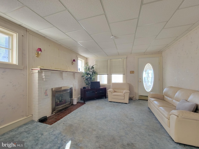 carpeted living area with a fireplace and a drop ceiling