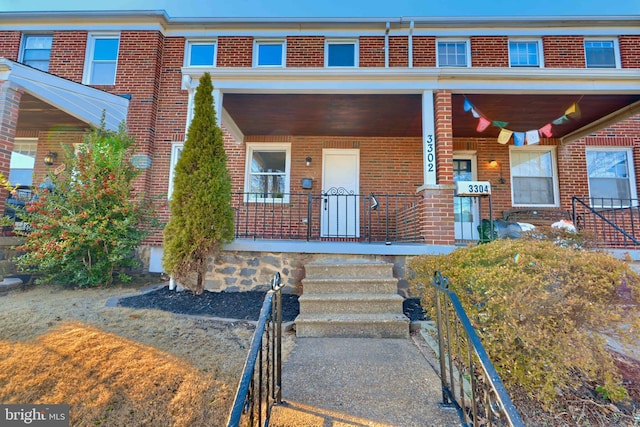 view of front facade featuring brick siding and a porch