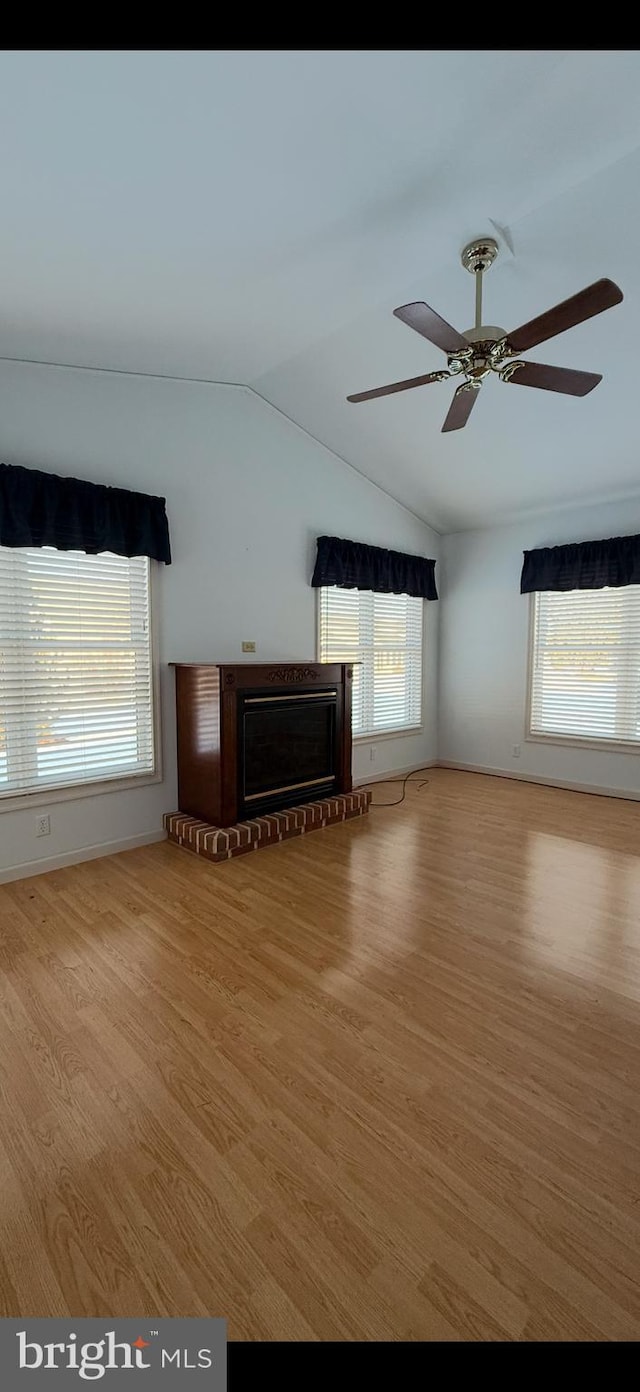 unfurnished living room featuring vaulted ceiling, light wood-style floors, and a healthy amount of sunlight