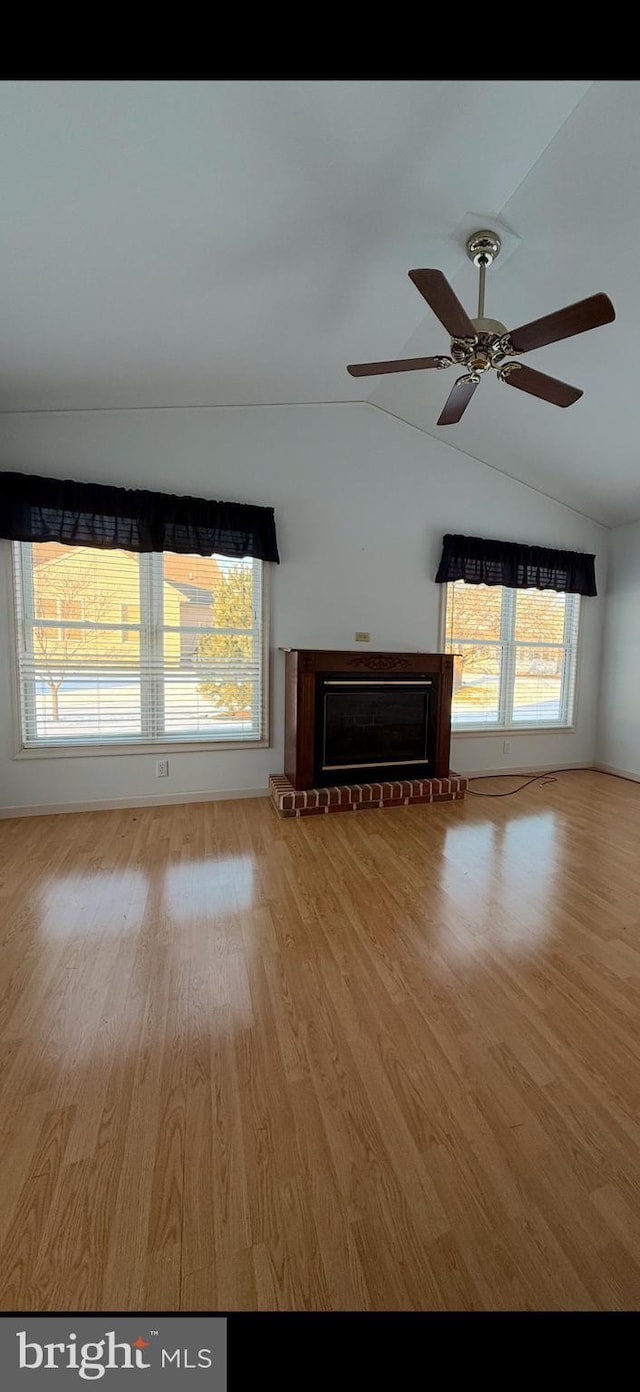 unfurnished living room featuring a ceiling fan, light wood-type flooring, a brick fireplace, and vaulted ceiling