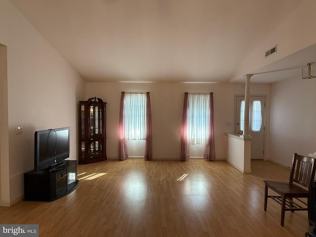 living area with baseboards, visible vents, decorative columns, and light wood finished floors