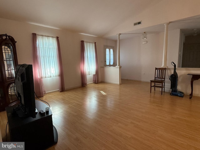 living area with visible vents, plenty of natural light, and decorative columns