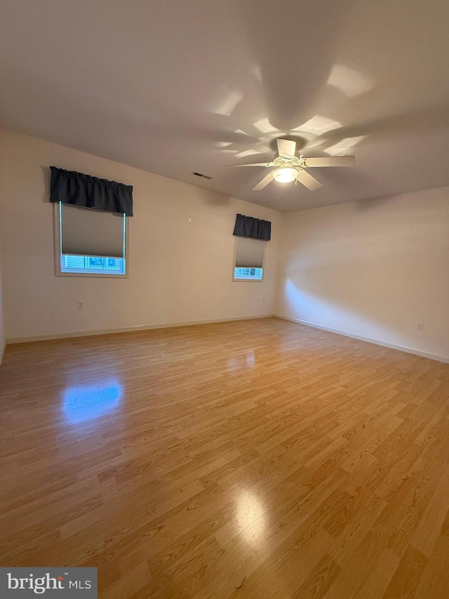 spare room with a ceiling fan, light wood-style flooring, and baseboards