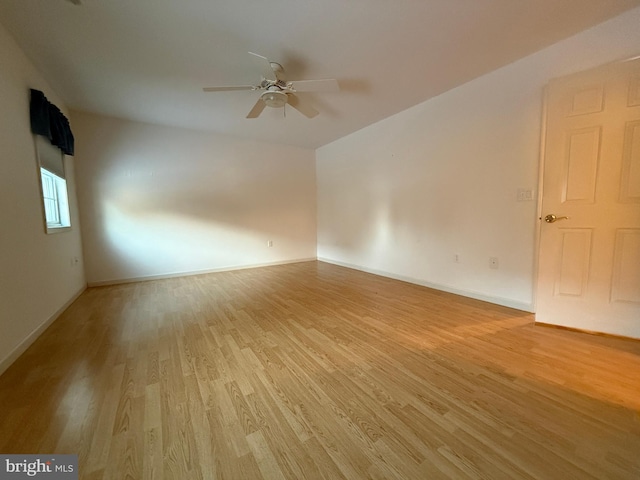 spare room with baseboards, light wood-style flooring, and a ceiling fan