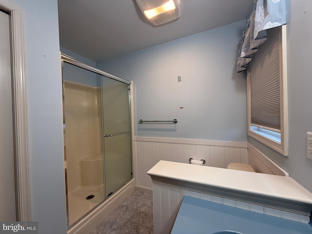 bathroom featuring wainscoting and a shower stall