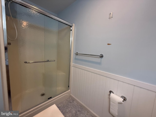 full bath featuring tile patterned flooring, wainscoting, and a shower stall