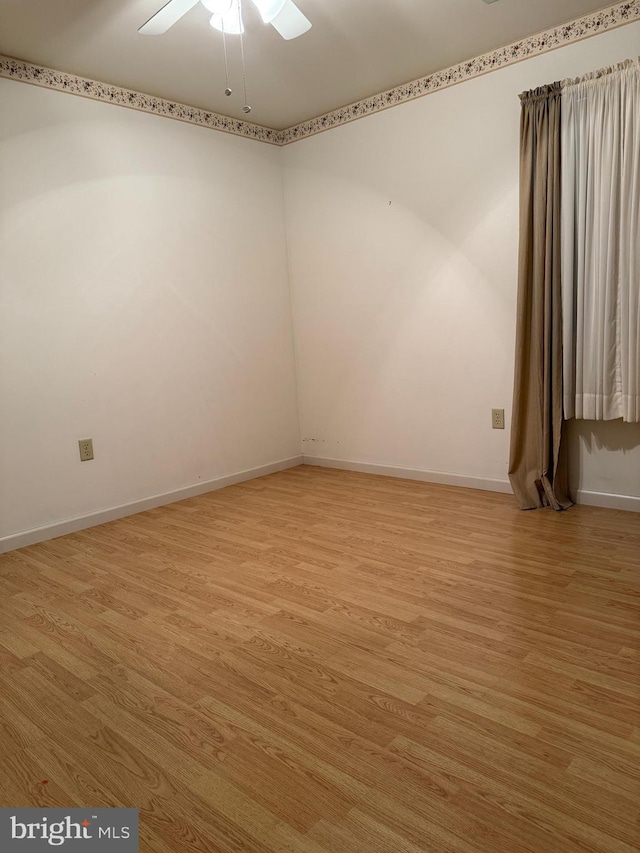 empty room featuring light wood-type flooring, a ceiling fan, and baseboards