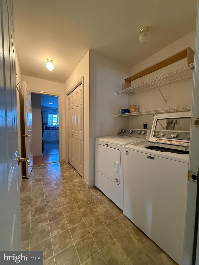 clothes washing area with tile patterned flooring, laundry area, baseboards, and washing machine and clothes dryer