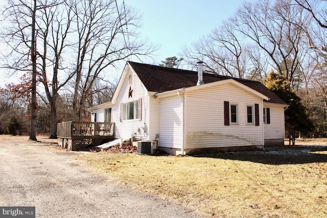 view of property exterior featuring a deck, central AC, a yard, and a shingled roof