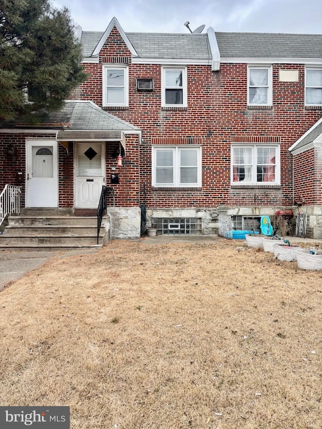 view of property with brick siding and a front lawn