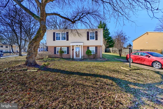 view of front of home with a front yard, fence, and brick siding