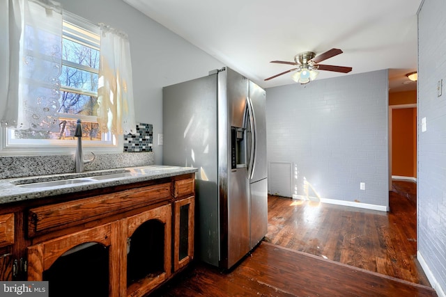 kitchen featuring ceiling fan, a sink, stainless steel fridge with ice dispenser, brown cabinetry, and dark wood finished floors