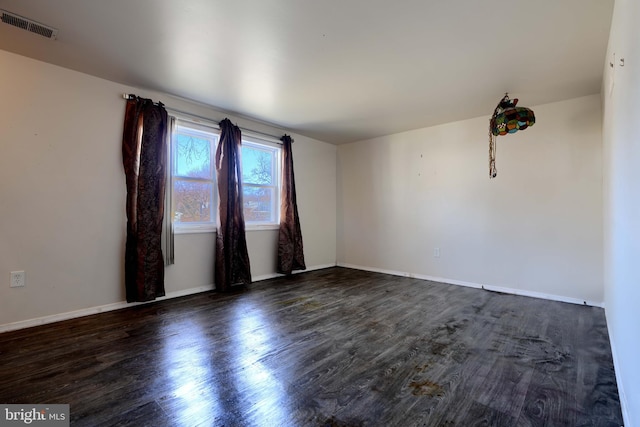 empty room with dark wood-style floors, baseboards, and visible vents