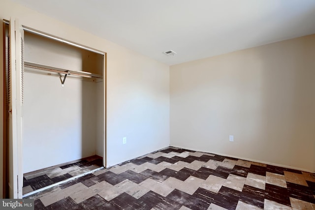 unfurnished bedroom with a closet, visible vents, and tile patterned floors