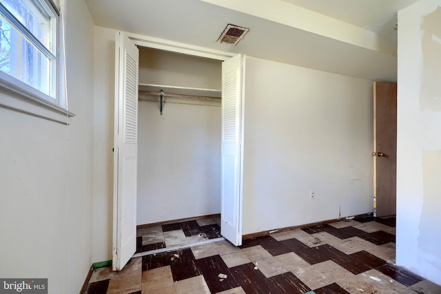 unfurnished bedroom featuring visible vents, baseboards, a closet, and tile patterned floors