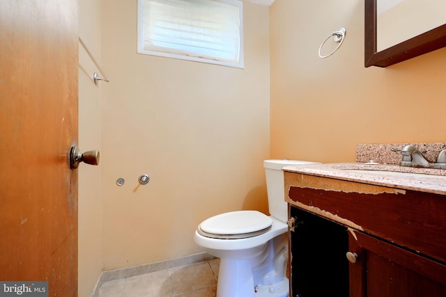 bathroom with toilet, tile patterned floors, baseboards, and vanity