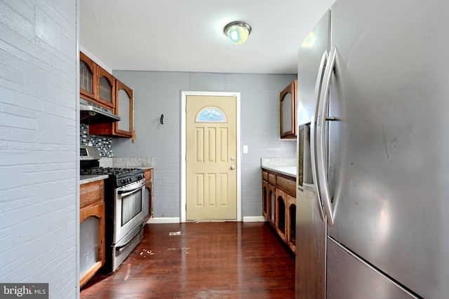 kitchen featuring stainless steel appliances, dark wood-type flooring, brown cabinetry, and under cabinet range hood