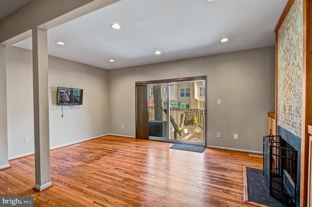 unfurnished living room with a fireplace, baseboards, wood finished floors, and recessed lighting