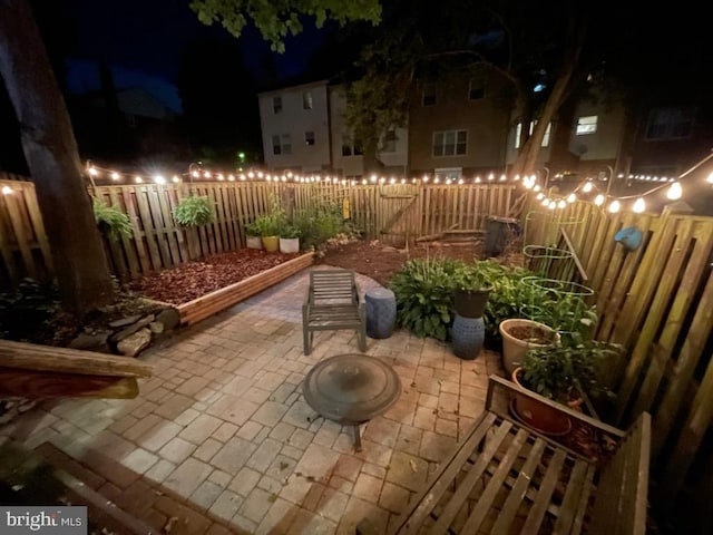 patio at night featuring a fenced backyard